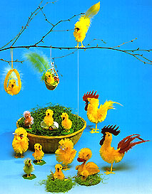 Osterdekoration: gelbe Küken, Hähne und Federn mit Eiern in einem Nest aus Ostergras
